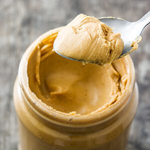 Creamy peanut butter and spoon on wooden background