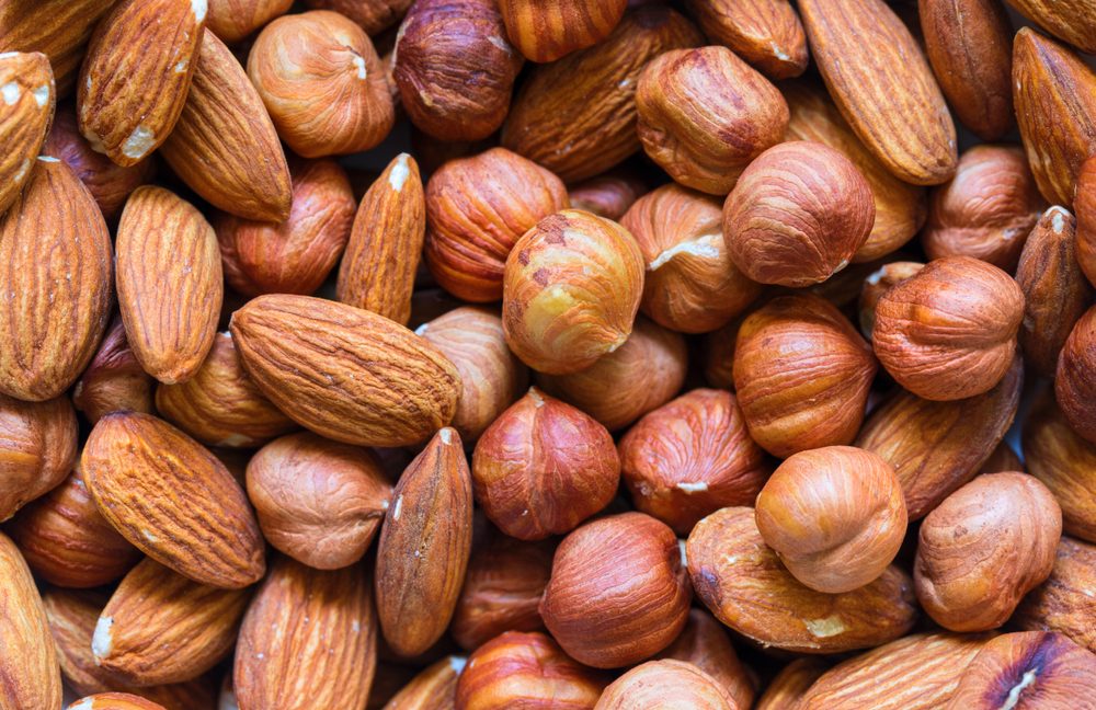 Nuts pile background. Cashew, almond, hazelnut mix closeup. Organic food rustic banner template. Tasty healthy snack.