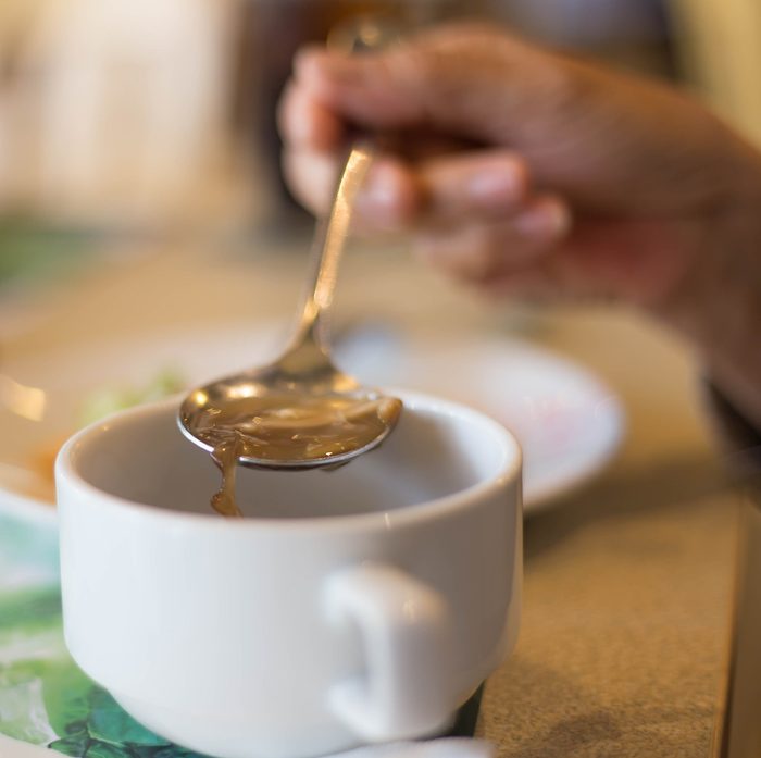 Blurred background woman's hand with the spoon while eating soup in the restaurant