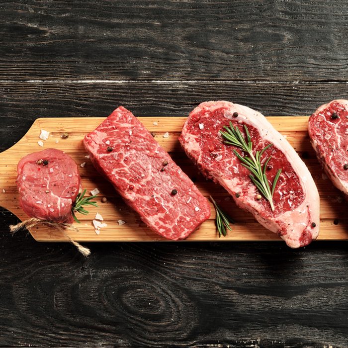 Fresh raw Prime Black Angus beef steaks on wooden board: Tenderloin, Denver Cut, Striploin, Rib Eye