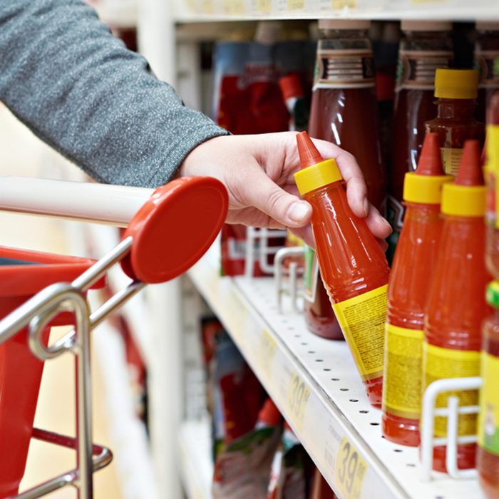 Hot chilli sauce in the hands of the buyer at the grocery store