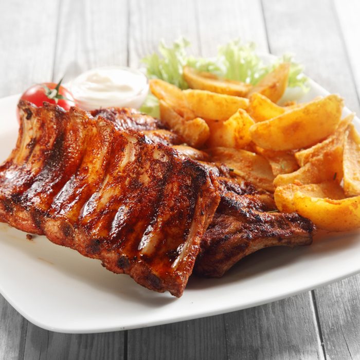 Close up Gourmet Main Dish with Grilled Pork Rib and Fried Potatoes on White Plate.