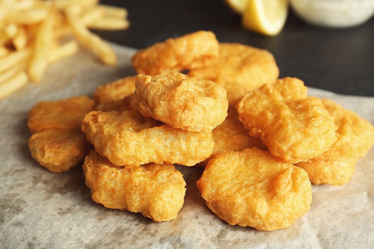 Tasty fried nuggets on paper, closeup