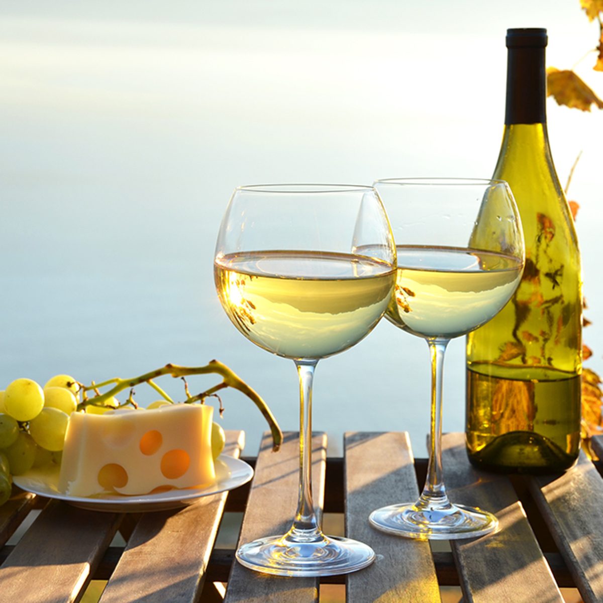 white wine and grapes against vineyards