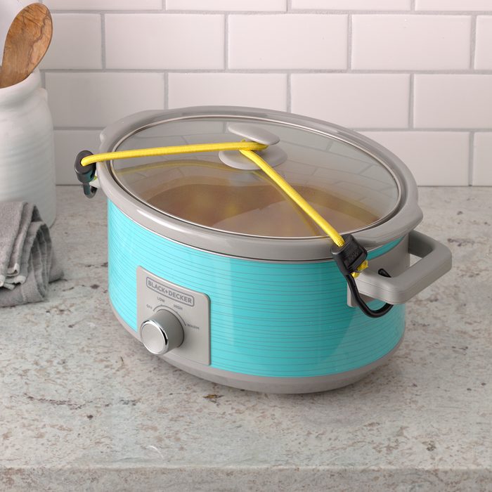 Slow cooker with bungee cord tied on for safe traveling.