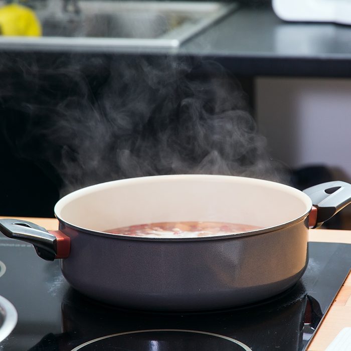 Saucepan with boiling clear soup on the plate