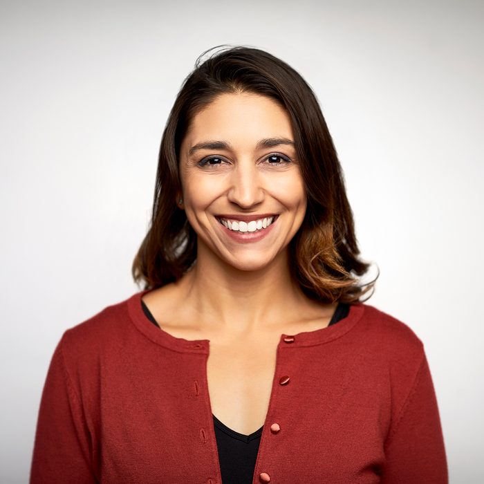 Portrait of young woman smiling. Close-up of beautiful female is against white background. She is wearing casuals.
