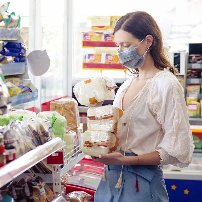 Woman wearing protective mask while grocery shopping in supermarket, Coronavirus contagion fears concept