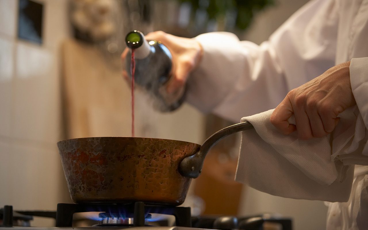 how to cook with wine Female Chef Pouring Wine Into Pan