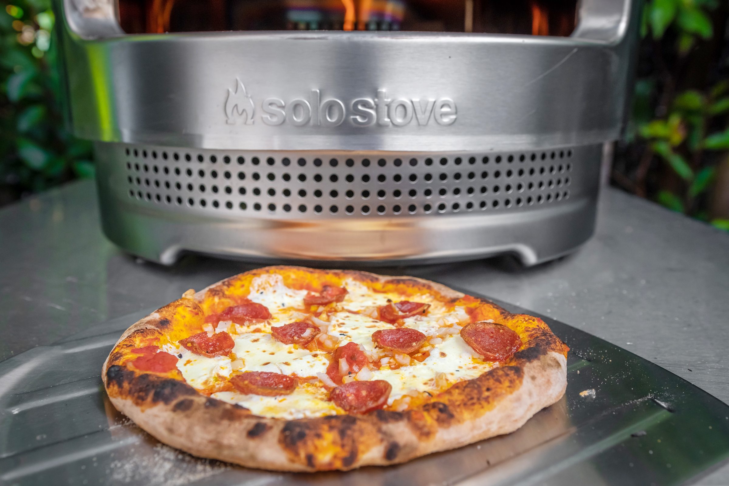 finished pepperoni and cheese pizza next to a solo stove pizza oven