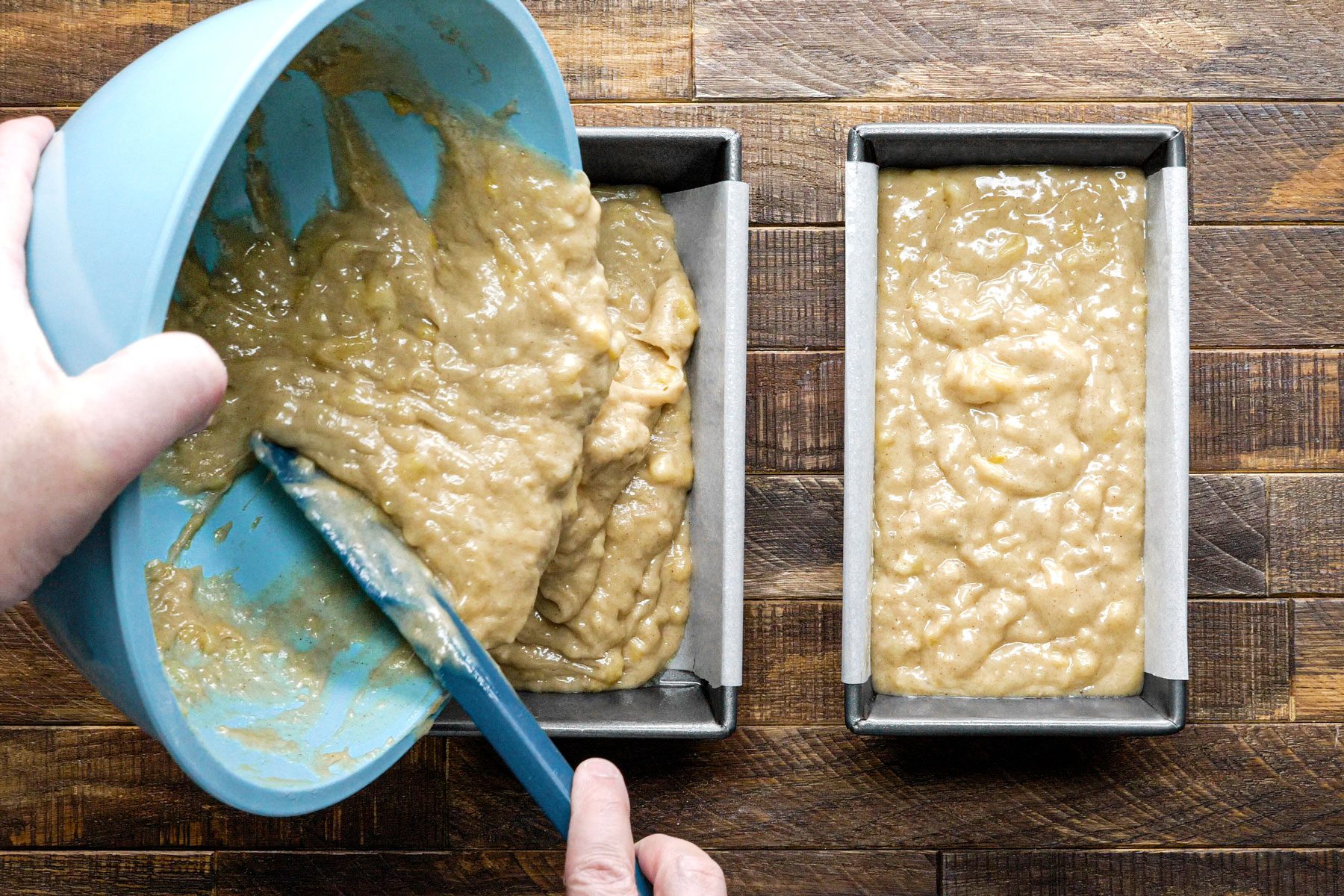 Pouring the batter into two pan from a large bowl using a spatula