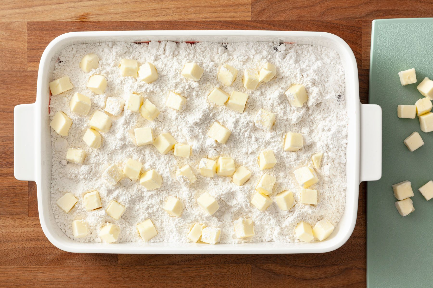 Butter cubes lined on cake mixture on a baking pan
