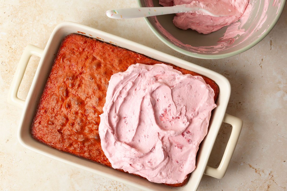 Step 4 of Taste of Home Raspberry Cake is to spread the frosting evenly over it. 