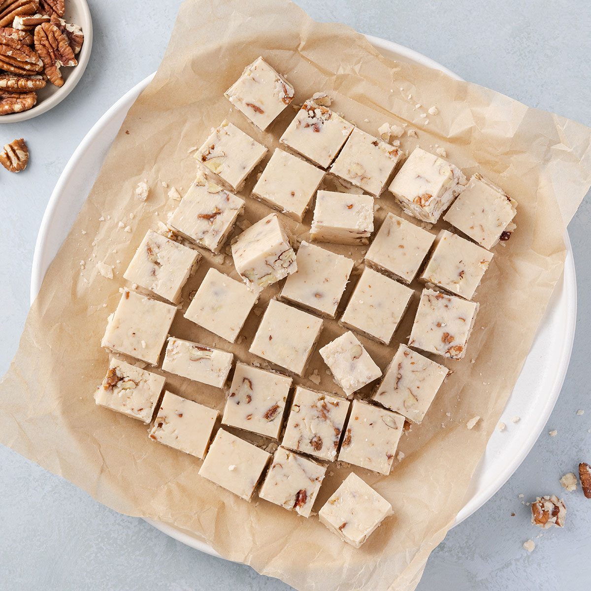 Butter pecan fudge ready and cut into 1 in squares, served on plate.