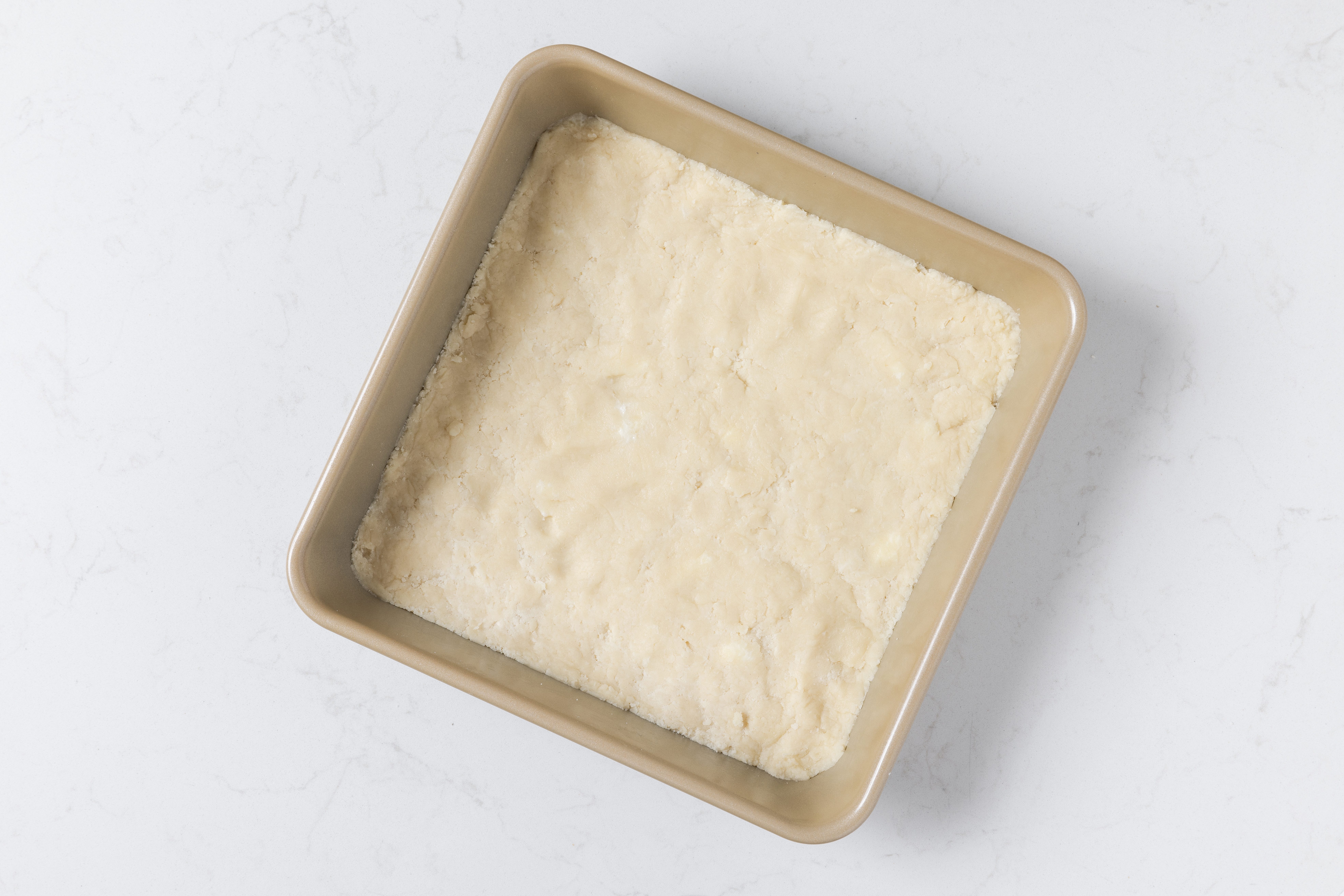 Lemon bars base in baking pan before going in the oven.