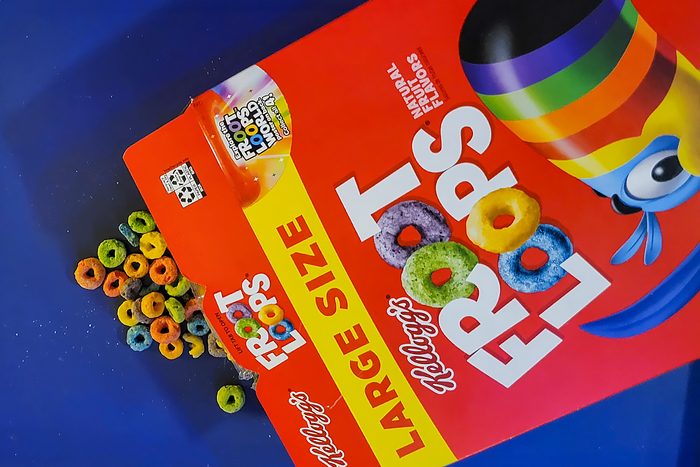 Box of Kellogg's Froot Loops cereal on a blue background. The box is open, showing colorful loops spilling out. The label reads "Large Size" and features a rainbow design.